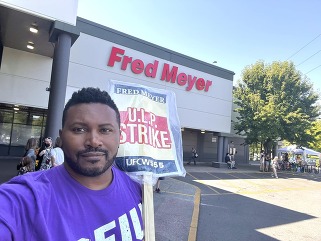 Rep Nelson holding a picket sign for UFCW55 outside of a Fred Meyer