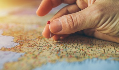 Stock photo of a hand putting a pin on a map