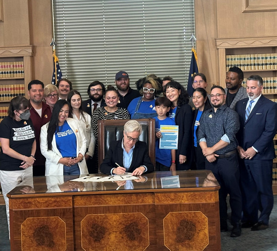 A group of advocates Governor Kotek as she signs a bill