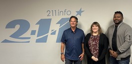 rep nelson with director and department lead of 211 in front of the 211 logo