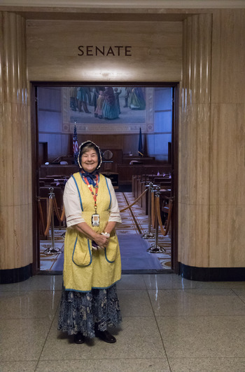 An oregon trail era costumed interpreter standing in front of the entrance to the House of Representatives
