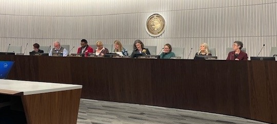 Rep sits at dais with committee