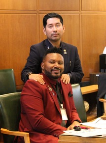 Rep Ruiz standing behind Rep Nelson sitting at his desk.