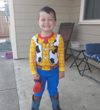 Preschool student wearing Sheriff Woody pajamas and standing in his backyard