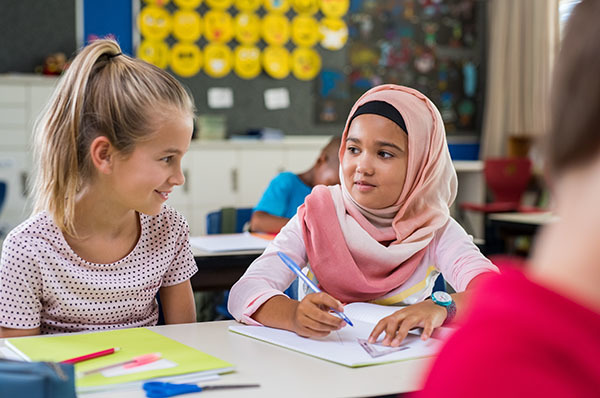 Two elementary students work at a desk together.