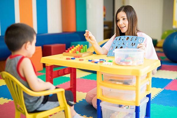 A young teacher works 1:1 with a student on letters and numbers.