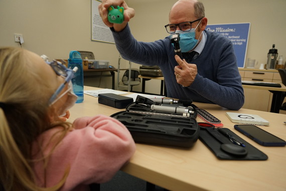 John Lowery holds up a green cat for a preschooler to look at