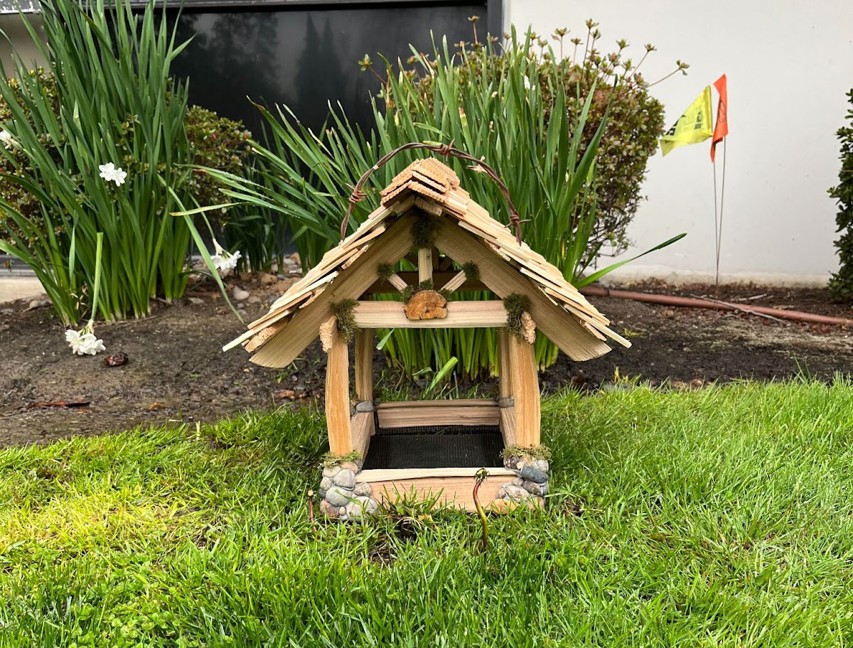 wooden birdhouse sits on the grass