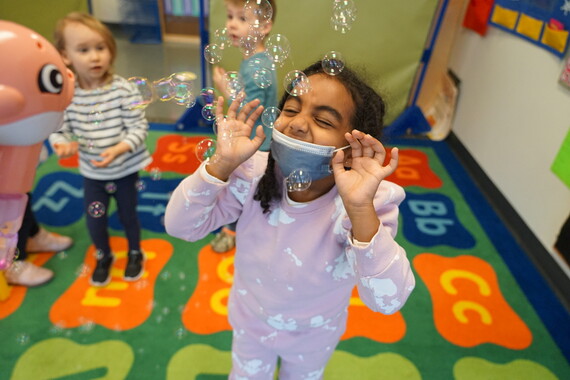 a preschooler enjoys playing in bubbles during a playgroup