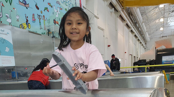an elementary school student holds a boat at a museum