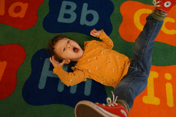 a preschooler lays down on a colorful carpet