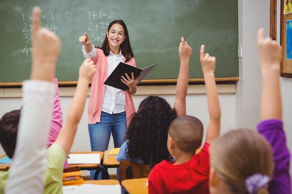 a teacher stands in front of a blackboard and calls on students