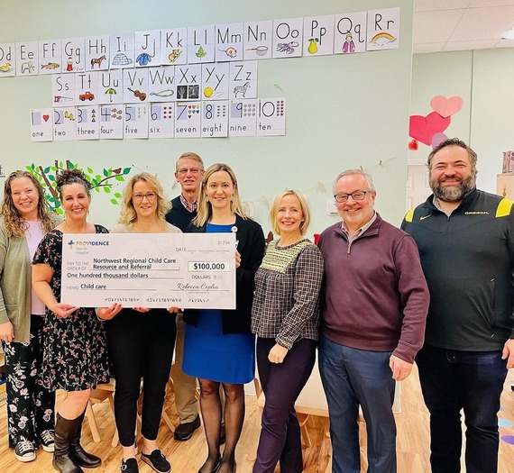 several people pose for a photo with an oversized check