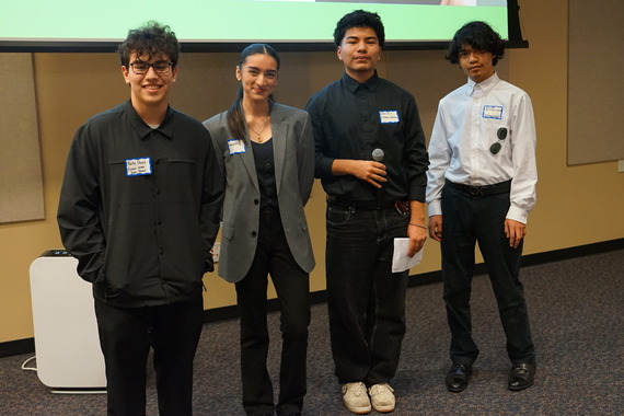 four high school students pose for a photo after speaking to the crowd