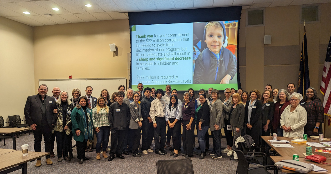 More than 40 people pose for a photo in a conference room