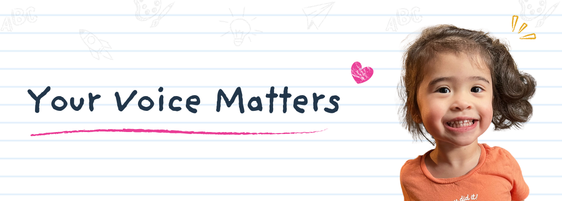 A toddler in an orange shirt smiles for the camera