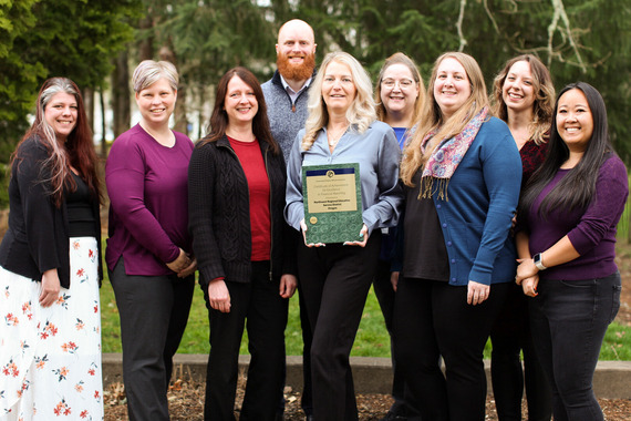 Nine members of the fiscal services team at Northwest Regional ESD pose for a photo in front of trees