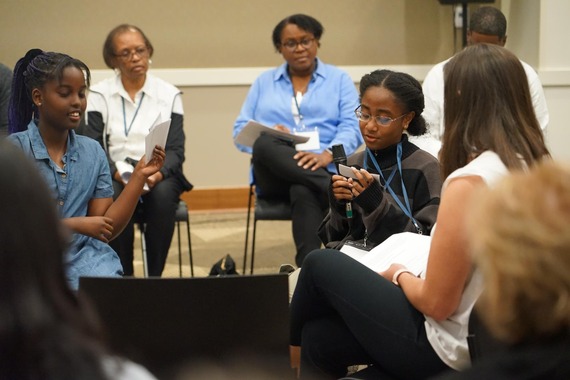 Ingrid (left) and Khloe, both fifth graders at Witch Hazel Elementary School, participate in a story circle. Adults surround them out of focus.