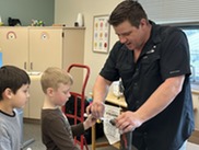 1st grade students sit and observe a plumber as he presents for career kits