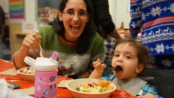 a mom smiles with a toddler during dinner