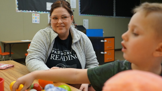 a teacher works with a kindergartener at a table