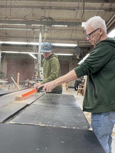 shop teacher assisting student in using a table saw