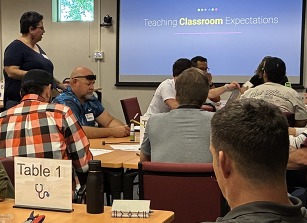 teachers sitting at table observing session facilitator
