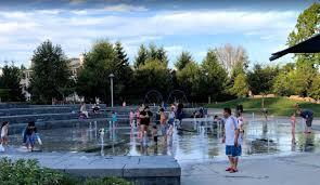 caregivers and children playing at a water feature on a sunny day
