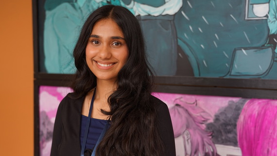 a high schooler poses for a photo in front of artwork
