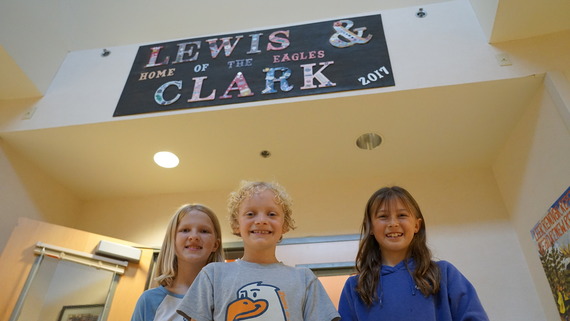 three elementary students in front of the library