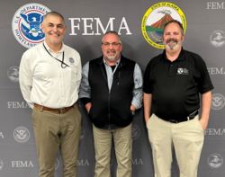 Three men stand in front of a FEMA backdrop