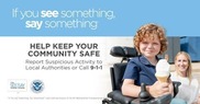 Smiling young boy with curly red hair, blue shirt, sits in wheelchair holding ice cream cone
