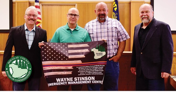 Man in green shirt, glasses holds a sign with a flag on it, he's flanked by three other men