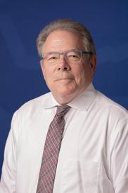 Man with sandy blonde hair, glasses, dress shirt and tie