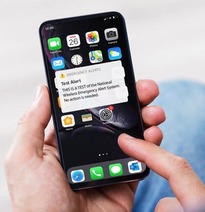 Hand holding cell phone with WEA Test Message