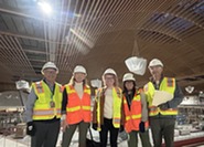 Two men flank three women, all in hard hats, during a tour of the Portland Airport expansion