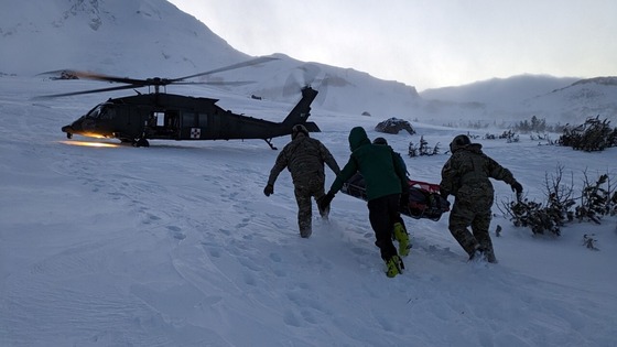 SAR Team carries an injured skier to a rescue helicopter on Mount Hood  