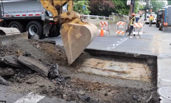 Base repair project front end loader scoops below the surface of SW Main Street