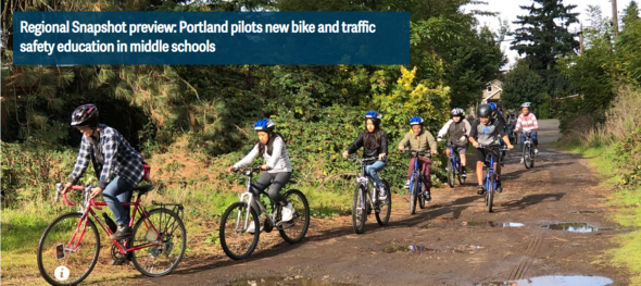 Students riding bikes in a line on a dirt road.