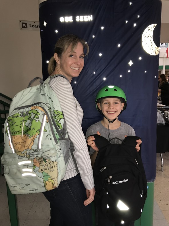 An adult and student show off their reflective sticker art.