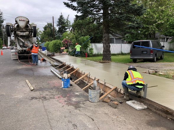 Construction workers smooth freshly poured concrete on NE 102nd Ave.