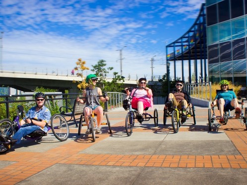 Five people sit on different types of three-wheeled Adaptive BIKETOWN bikes