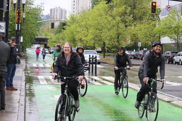 Smiling bike riders in the rain on Better Naito Forever