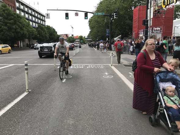 Better Naito in 2017, people walking in the space behind them a large crowd spills into the roadway from the ticket line