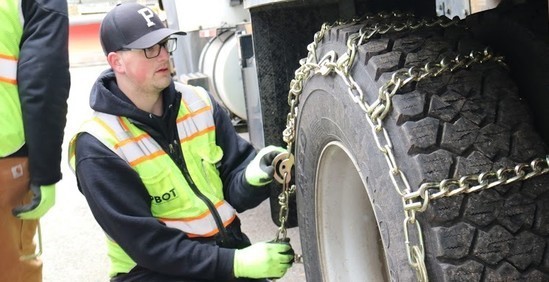 PBOT staff install chains on a truck tire