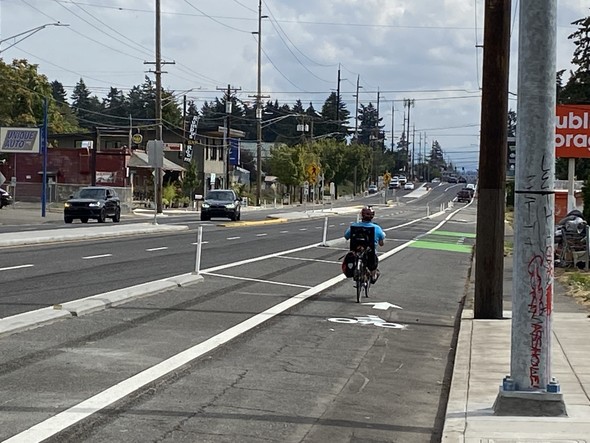 Person biking at SE Division at 104th a new protected bike lane sidewalks median part of PBOT Safety Project