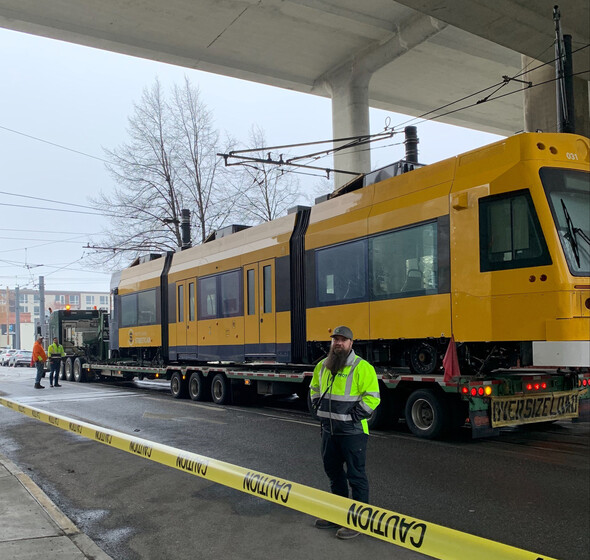 PBOT Streetcar Maintenance Supervisor Lee McIntire stands in front of the newly delivered streetcar as it sits on a truck trailer. 