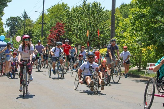 This image shows a group of adults and kids riding bicycles including some recumbent bikes at a Sunday Parkways event