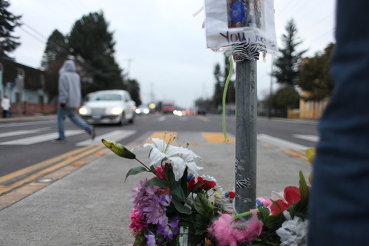 A floral memorial for a fatal traffic victim in the medium of a two-way street in front of a crosswalk.