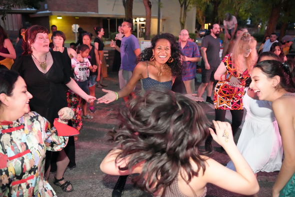 A crowd of smiling people dance after dark at St Johns Plaza